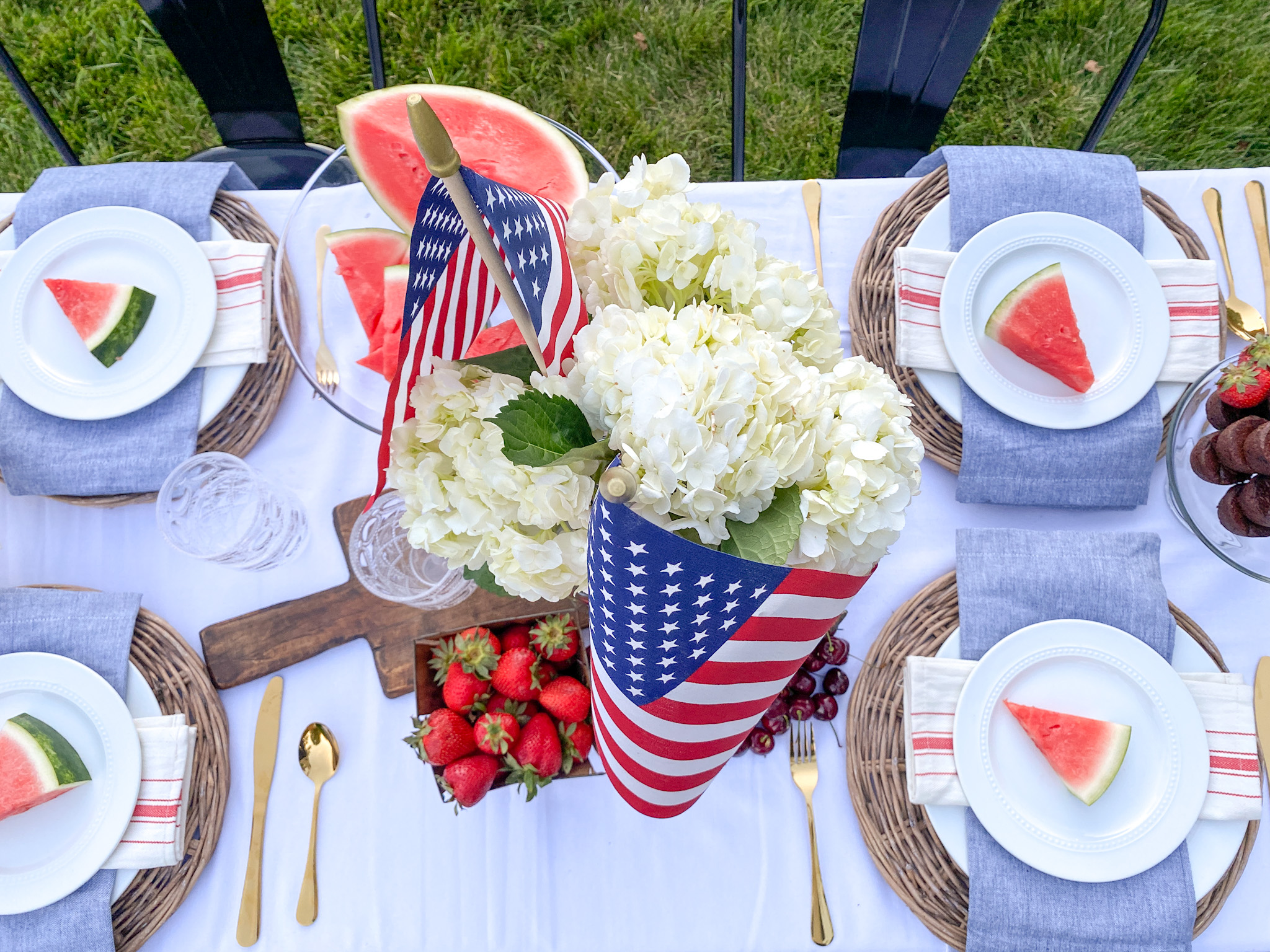 Overhead view of red, white, and blue patriotic table set for a backyard BBQ party for Memorial Day