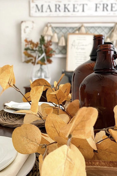 Vintage amber bottles in a dough bowl with fall foliage