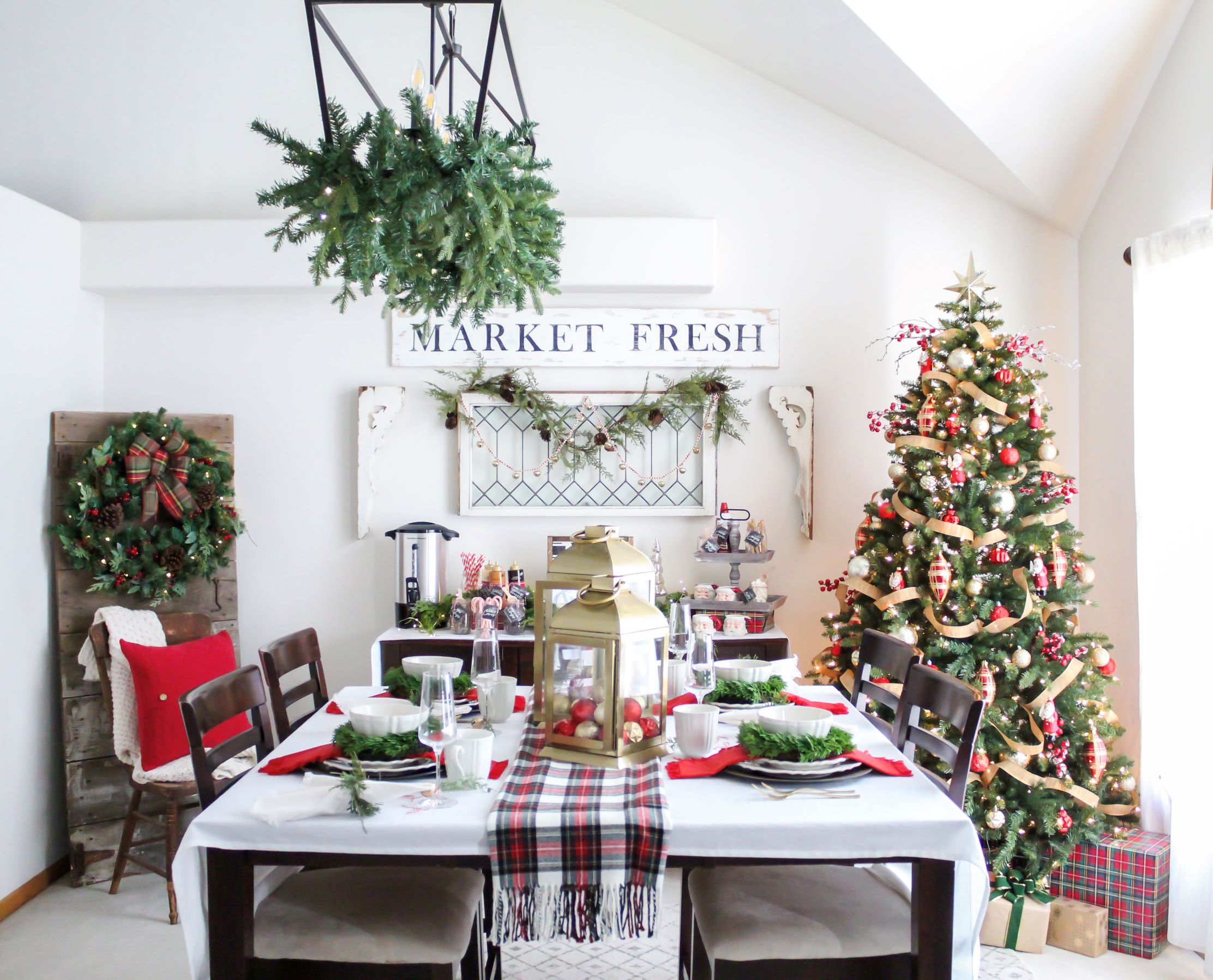 Dining room decorated for Christmas with red and white decor, a table set for Christmas brunch, and a hot cocoa bar set up on the buffet table. 