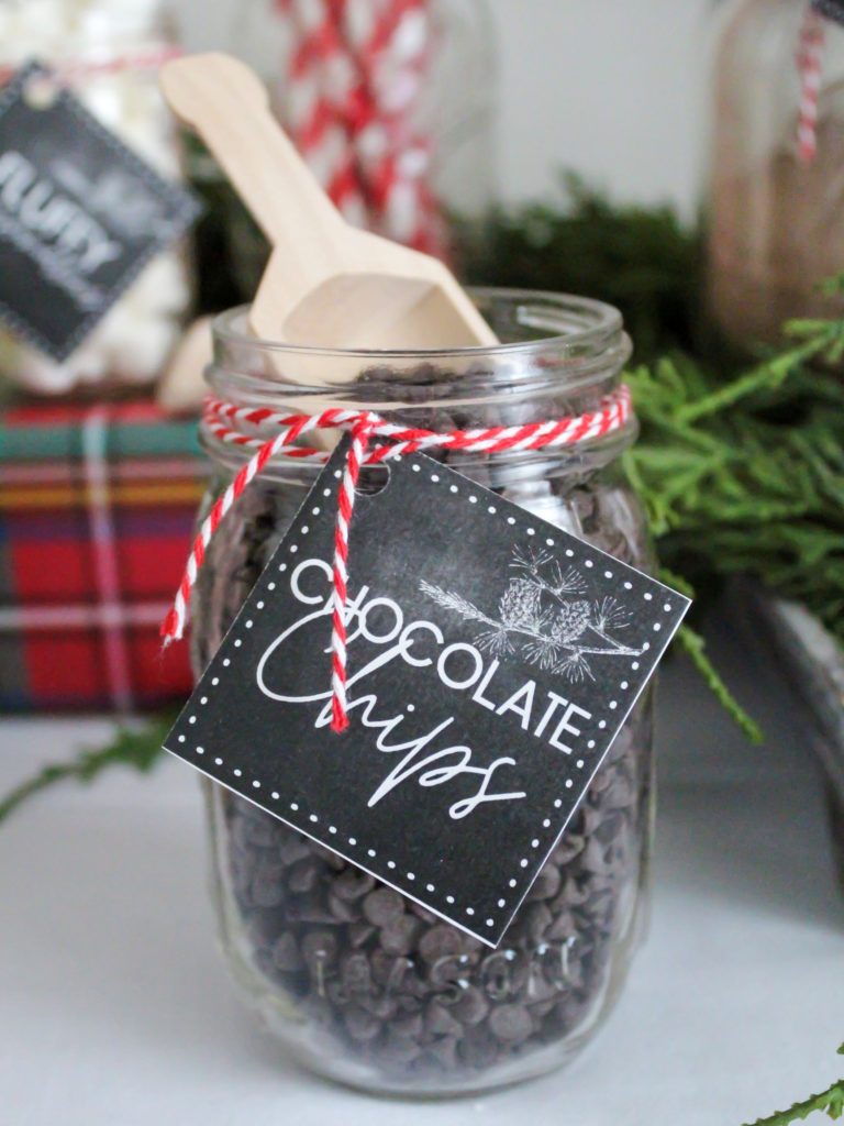 Small mason jar filled with mini chocolate chips and a small wooden scoop for a hot cocoa bar