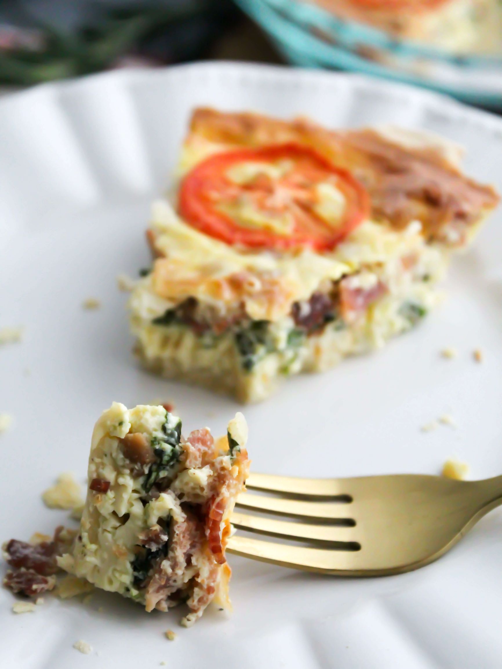 Close up bite of bacon and spinach quiche made for Christmas on a gold fork