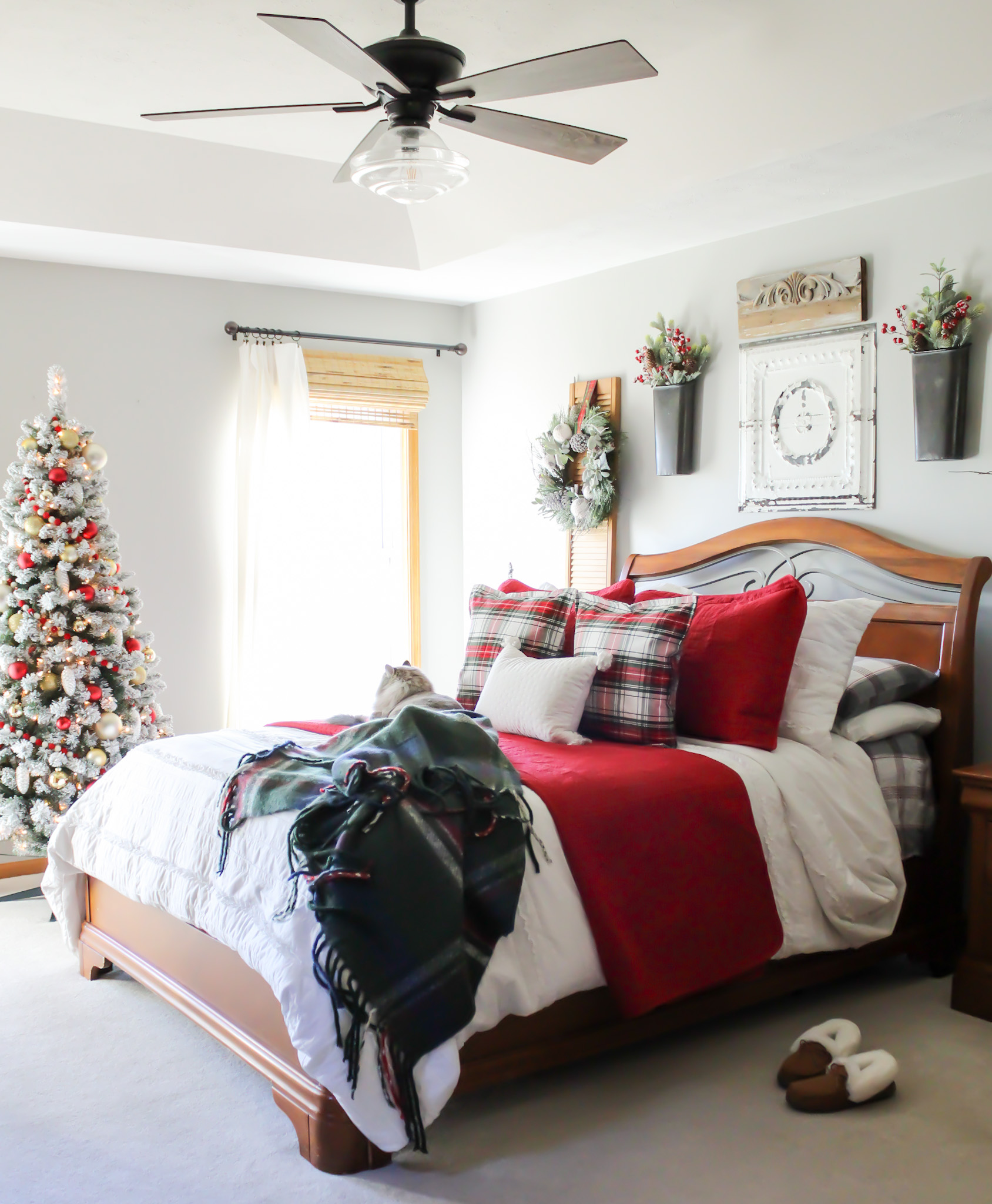 Traditional Christmas decor in the bedroom with red bedding, flocked tree with red and white ornaments red holiday bedding with and plaid pillows.