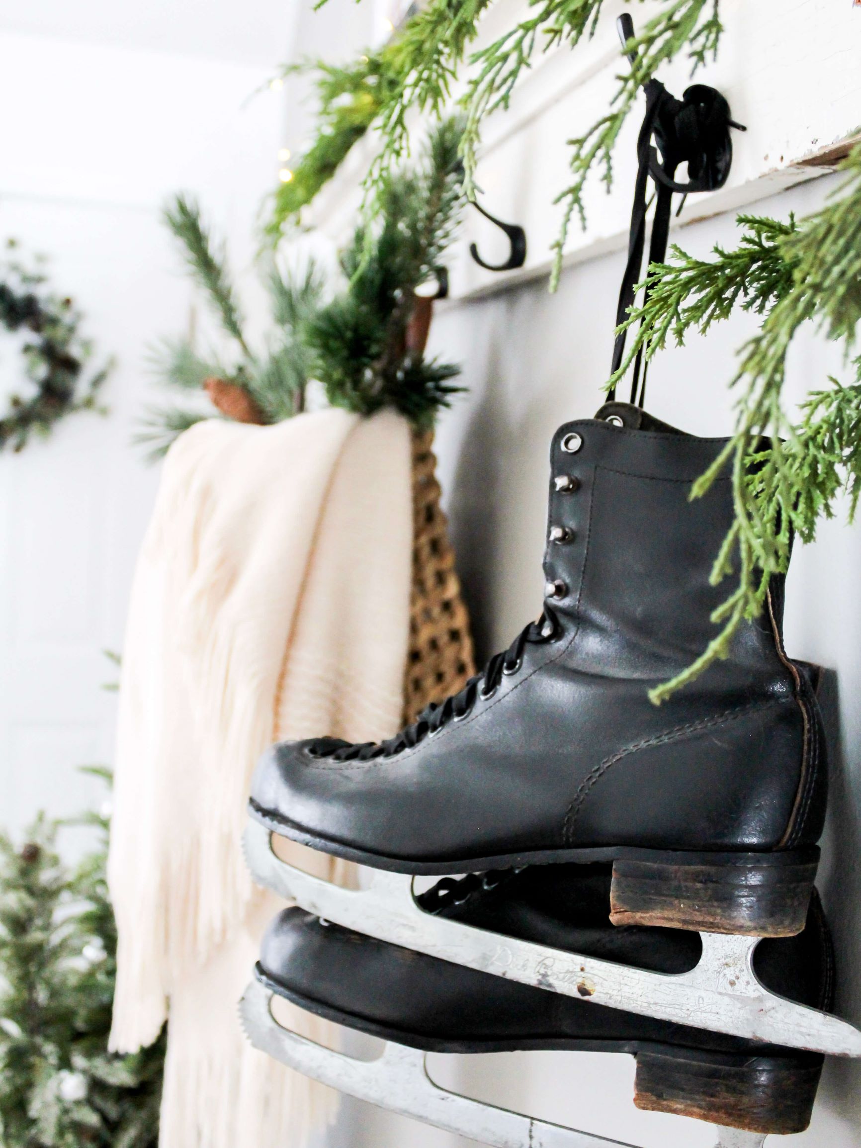 Vintage black ice skates hanging from hooks on a shelf in the entry used for winter decor