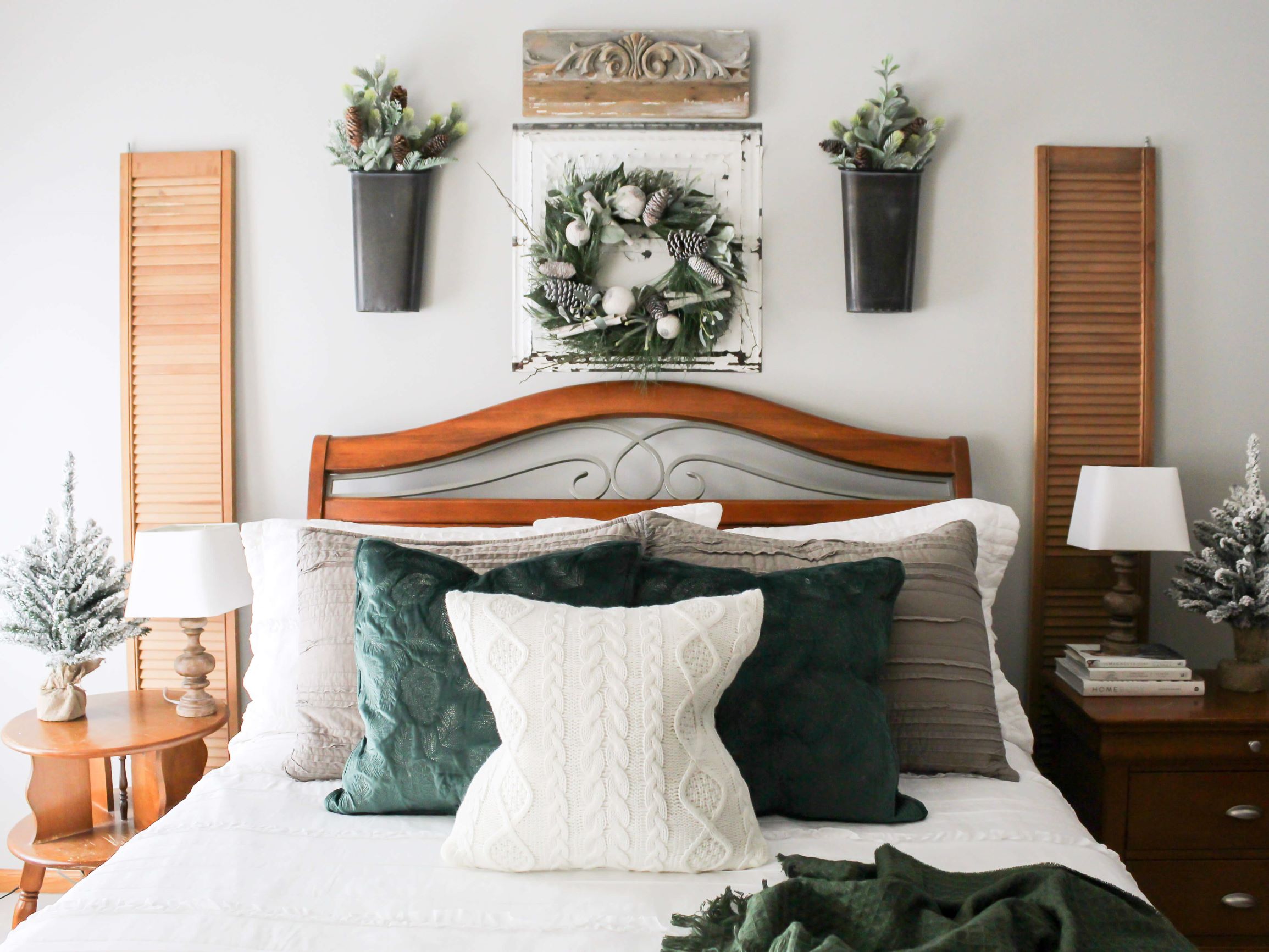 Cozy green and white winter bedding in the master bedroom with greenery decor and a winter wreath on the wall