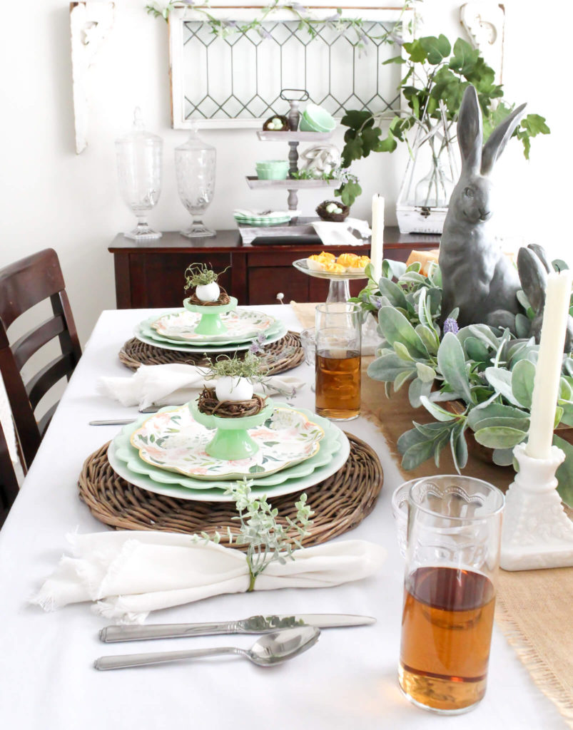 Easter tablescape with wicker chargers, jadeite dishes, a dough bowl centerpiece and bunnies