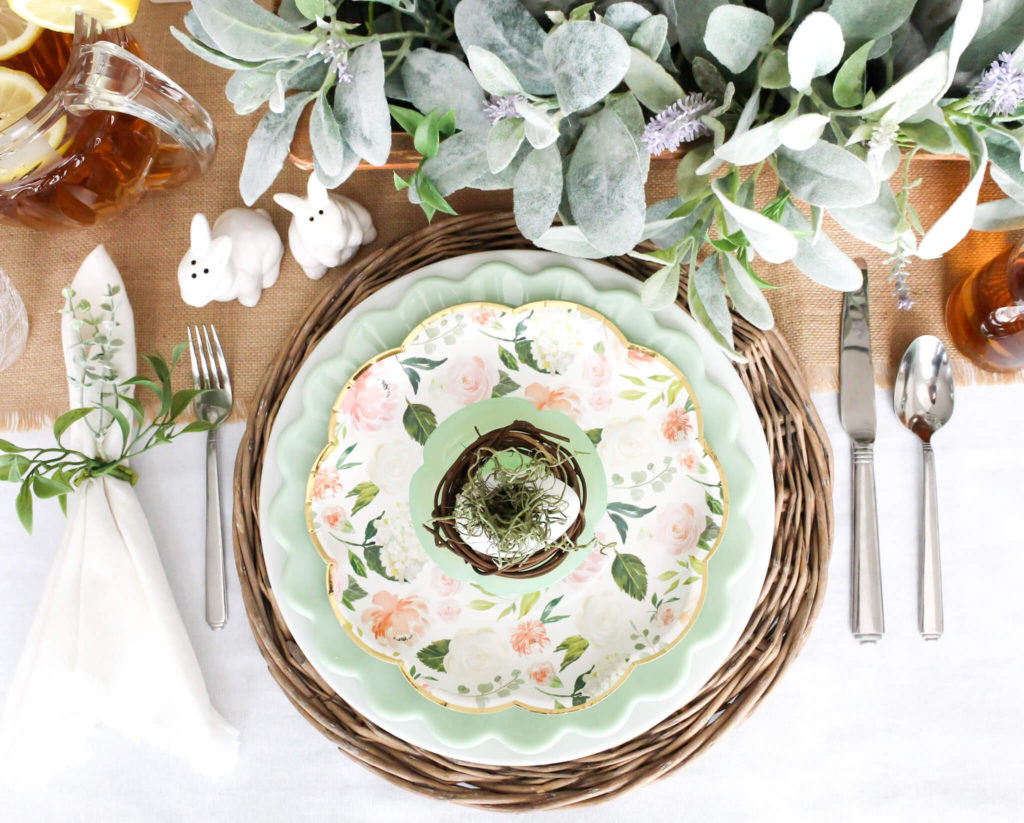 Overhead view of easter place setting with jadeite dishes, floral paper plates, and bunny salt and pepper shakers