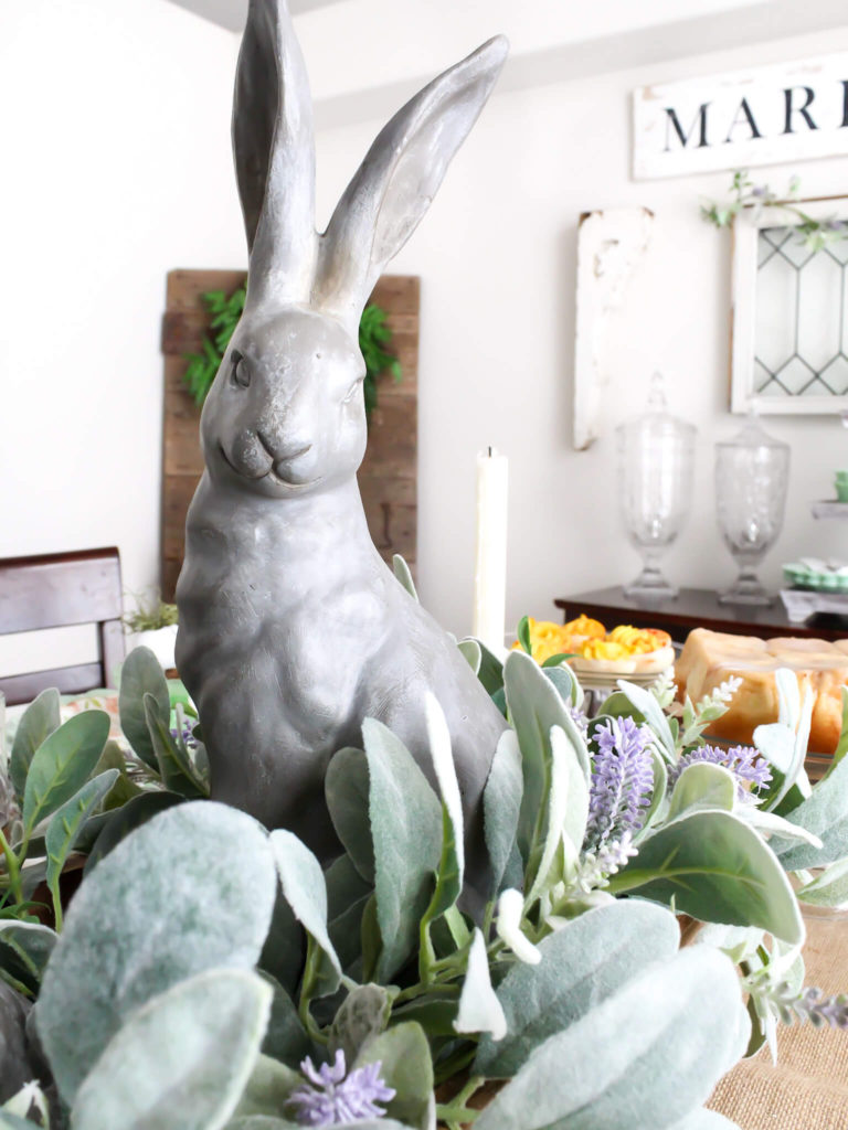 Close-up view of a spring centerpiece with a reproduction dough bowl styled with Pottery Barn Essex Easter bunnies, lambs ear greenery, and lavender 