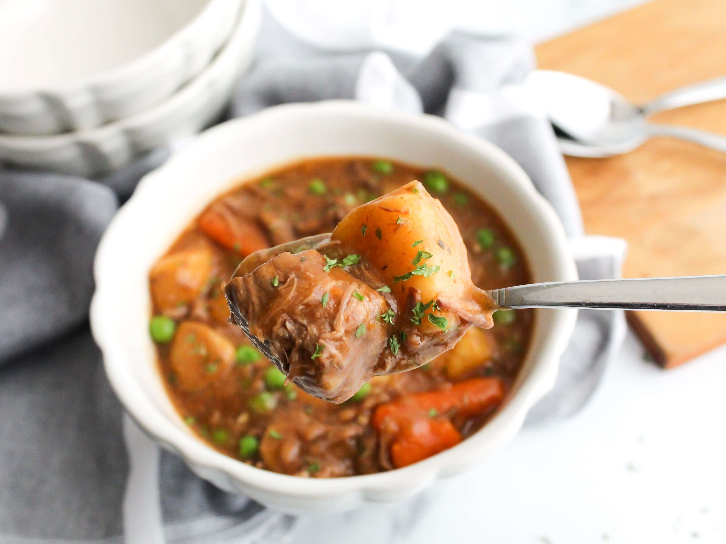 Bowl of crockpot beef stew with a spoonful of the stew showing a closeup of the beef and vegetables