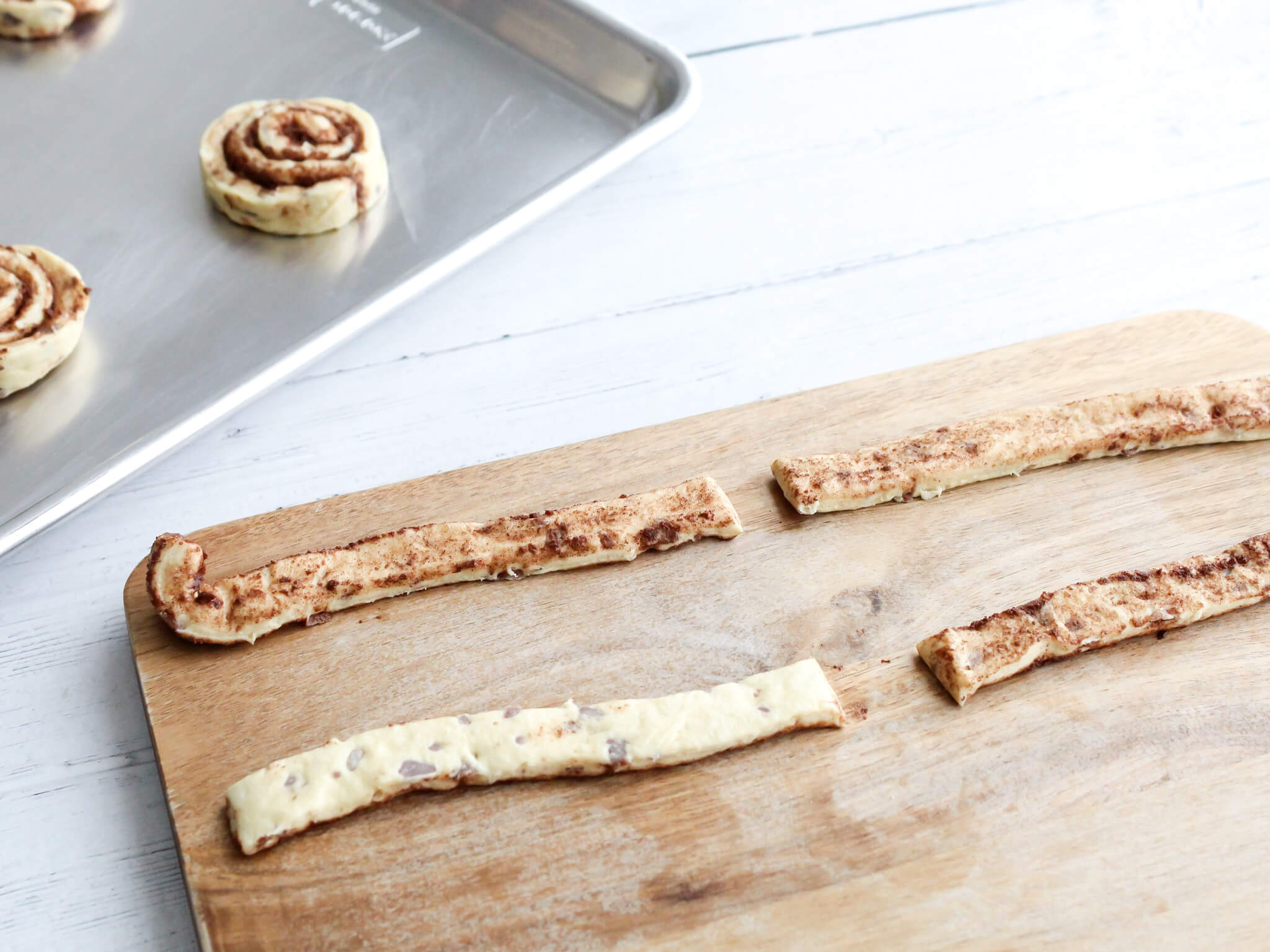 Pieces of cinnamon roll dough cut into strips for Easter bunny cinnamon rolls