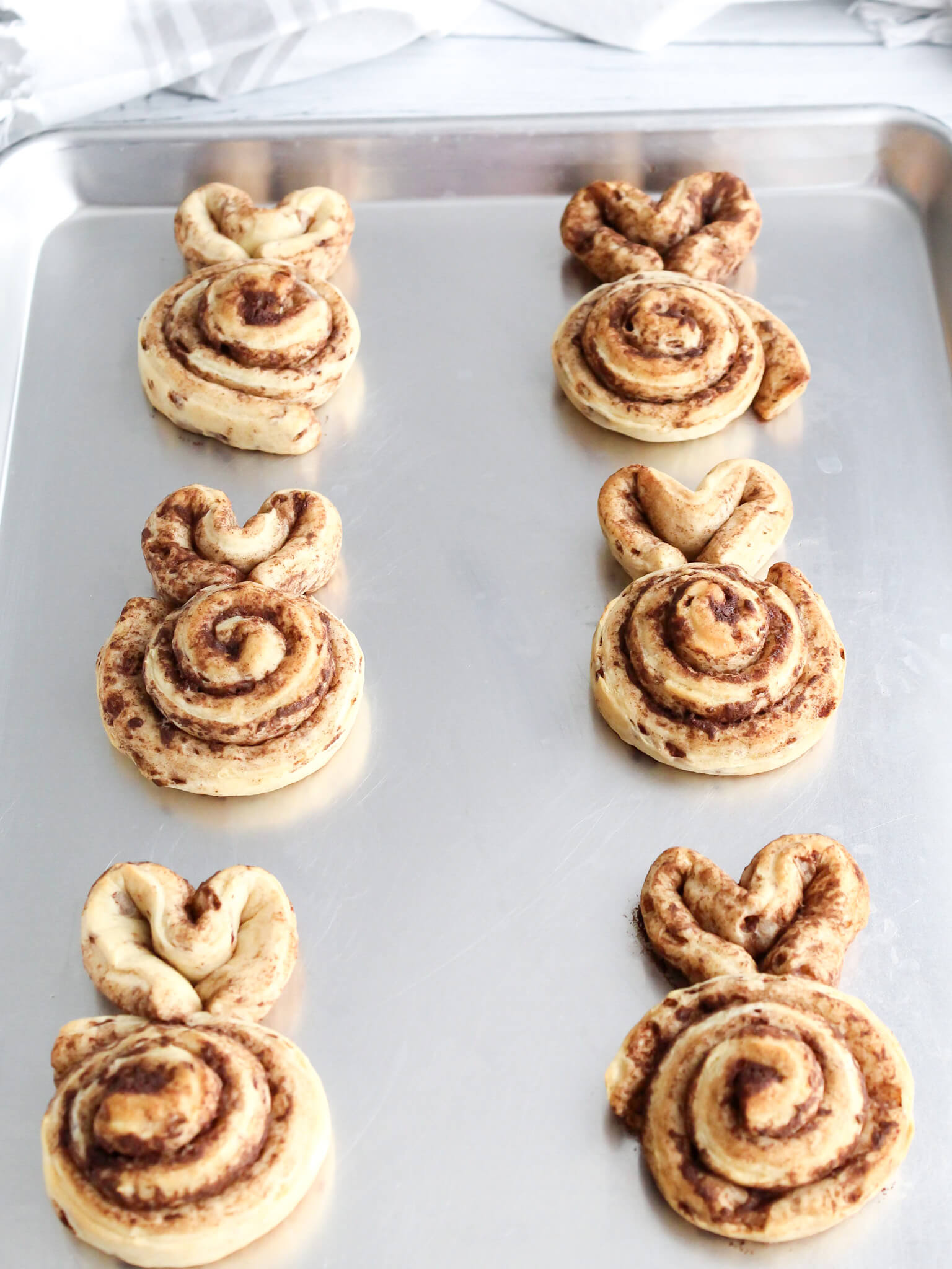 Bunny shaped cinnamon rolls on a sheet ready to be baked