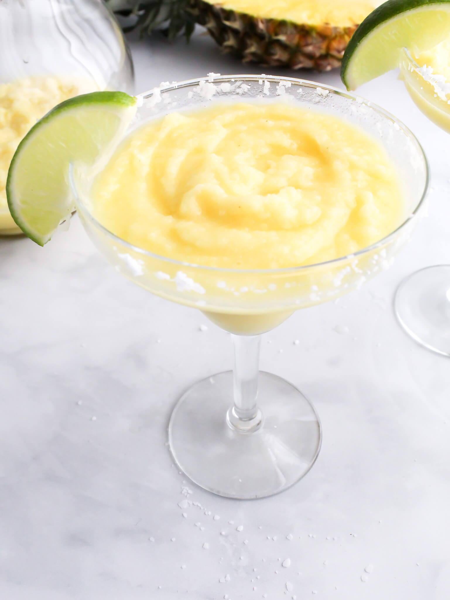 Frozen Pineapple Margarita in a cocktail glass with a lime wedge garnish