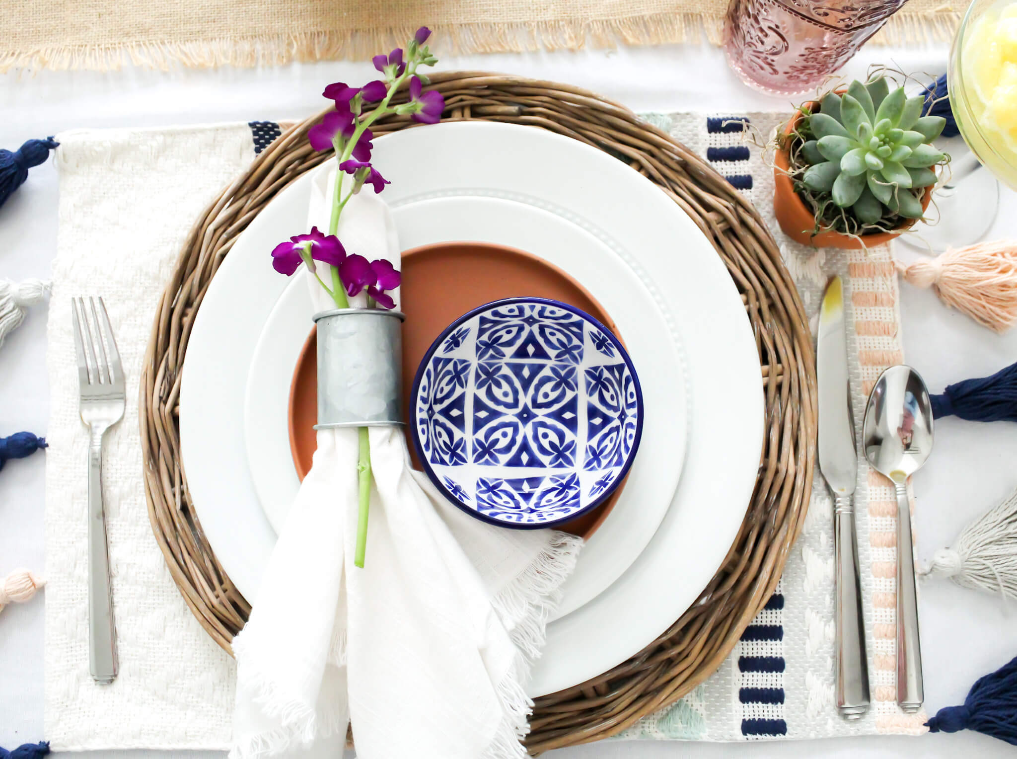 Over head view of a place setting for a festive Cinco de Mayo party with small succulents in terra cotta pots, and bright Mexican dishware