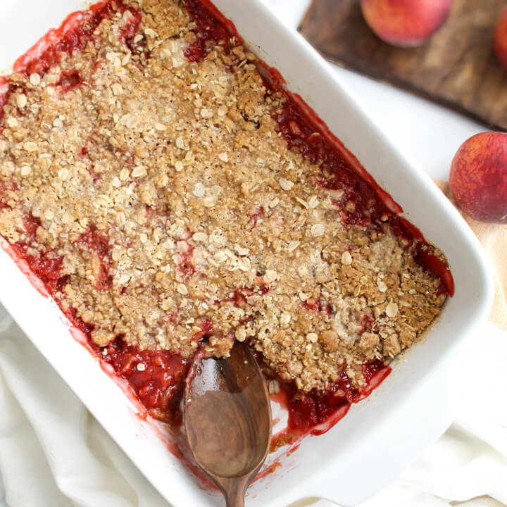 Old Fashioned Strawberry Peach Crisp in a Baking Pan with a Wooden Spoon