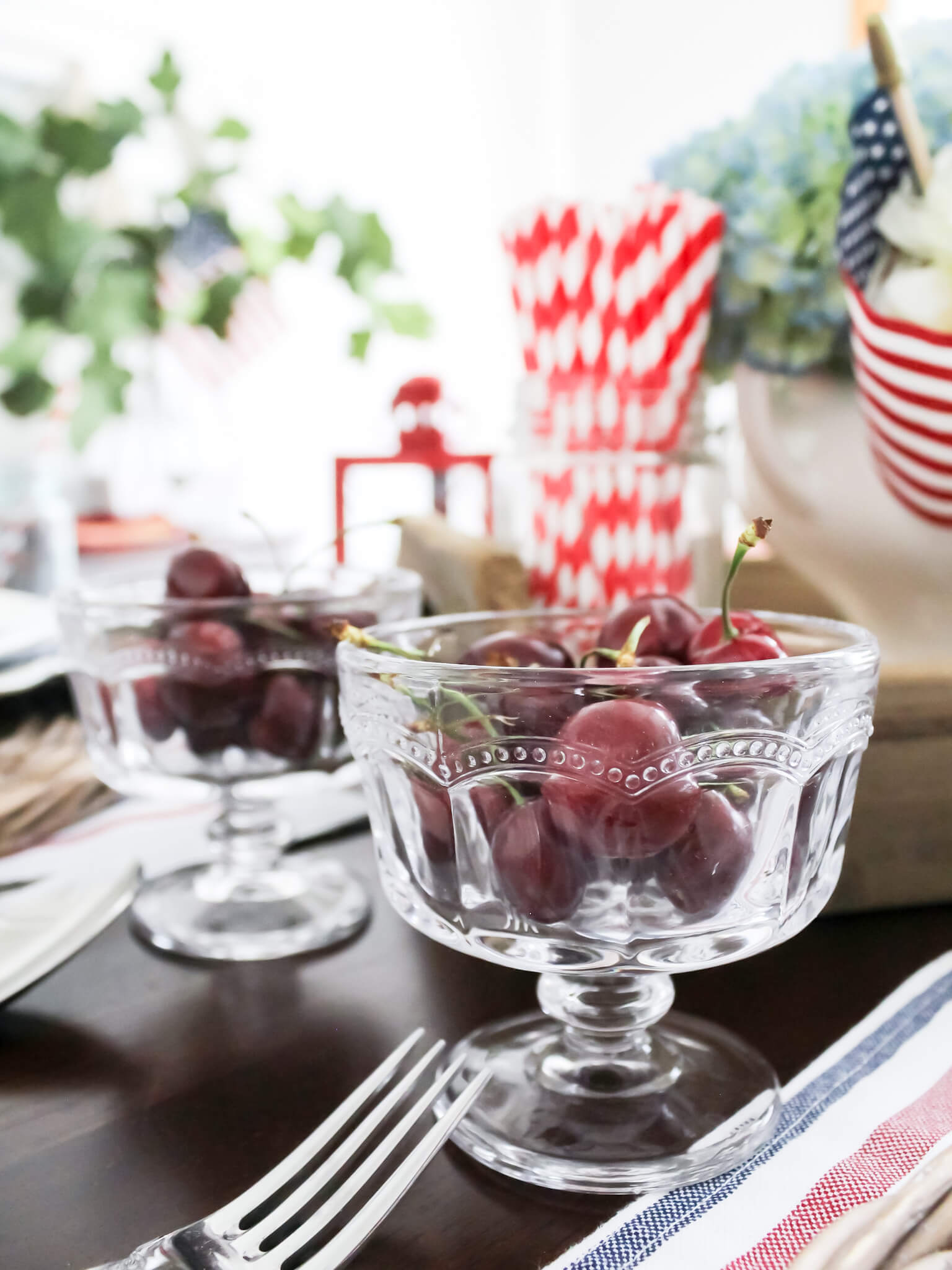 small glass dessert dishes filled with fresh cherries on a patriotic 4th of July tablescape