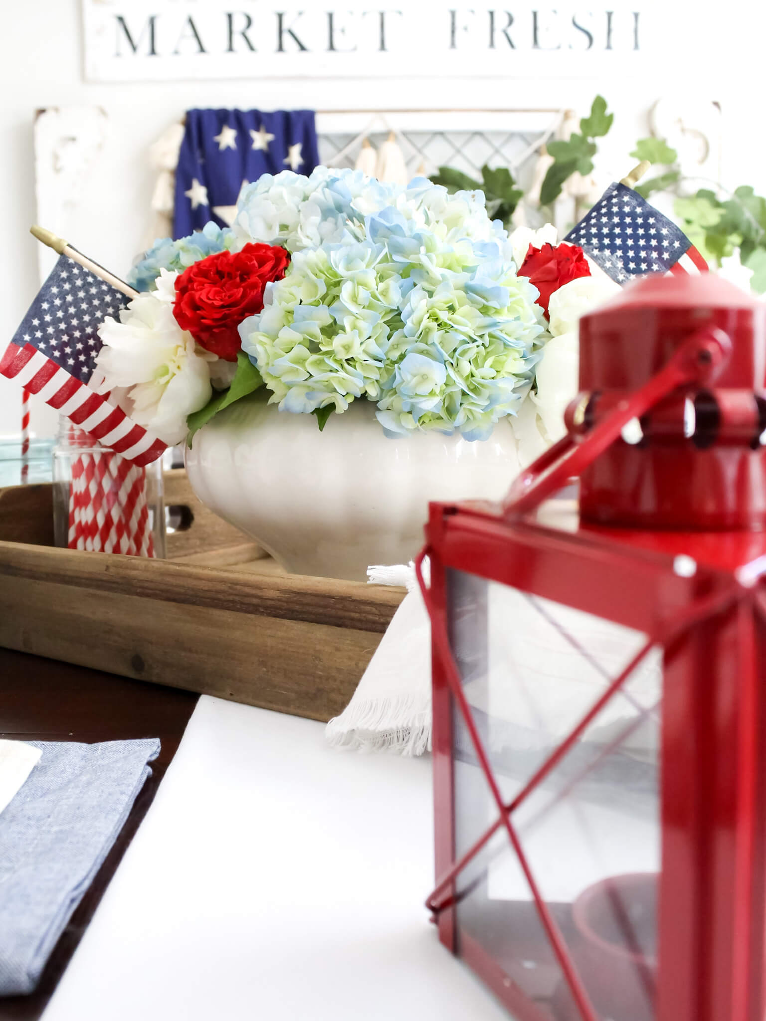 Red, white and blue patriotic flower centerpiece with American flags styled on rustic wood tray