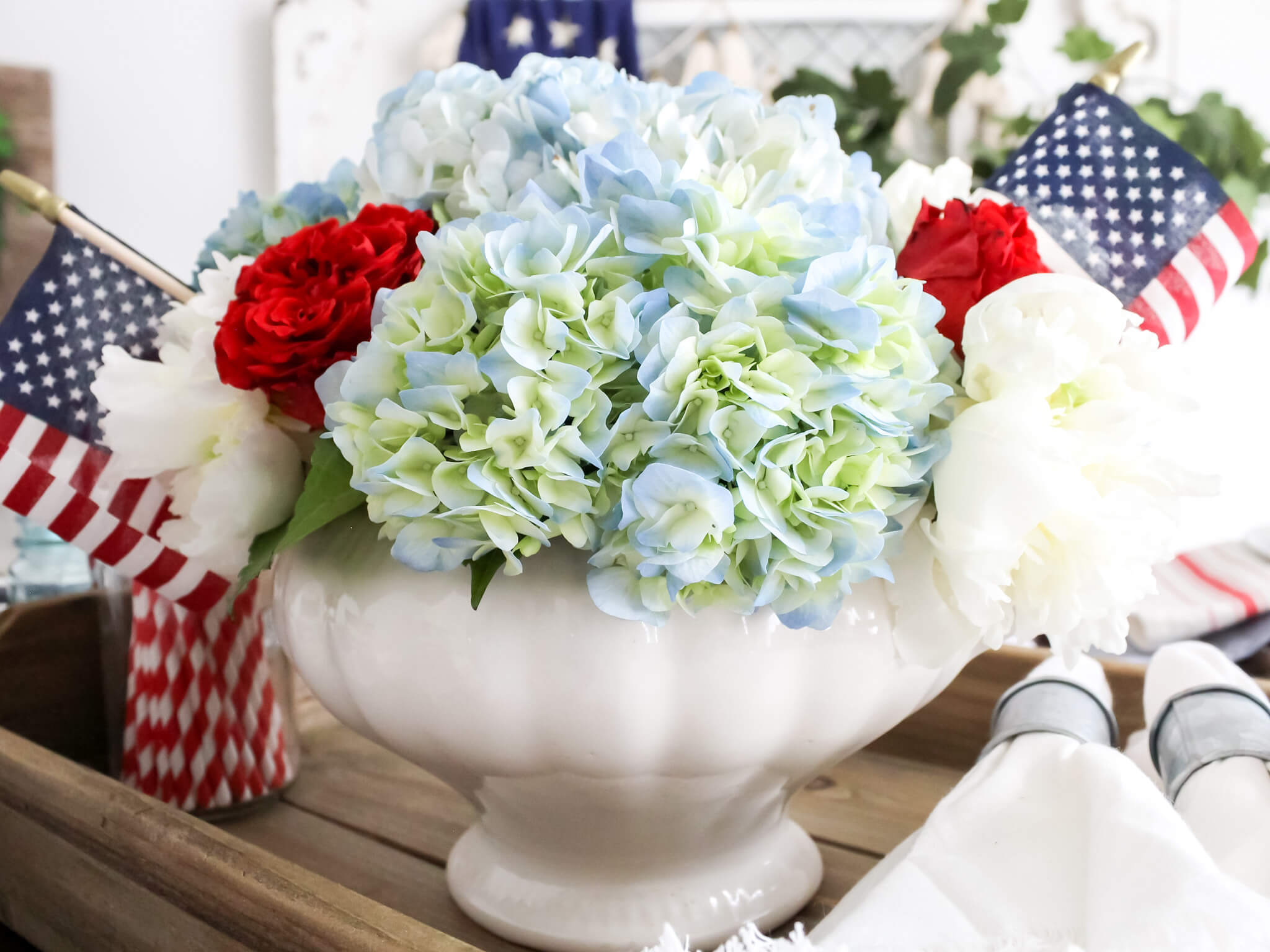 Close-up of red, white, and blue Fourth of July floral centerpiece with small American flag picks