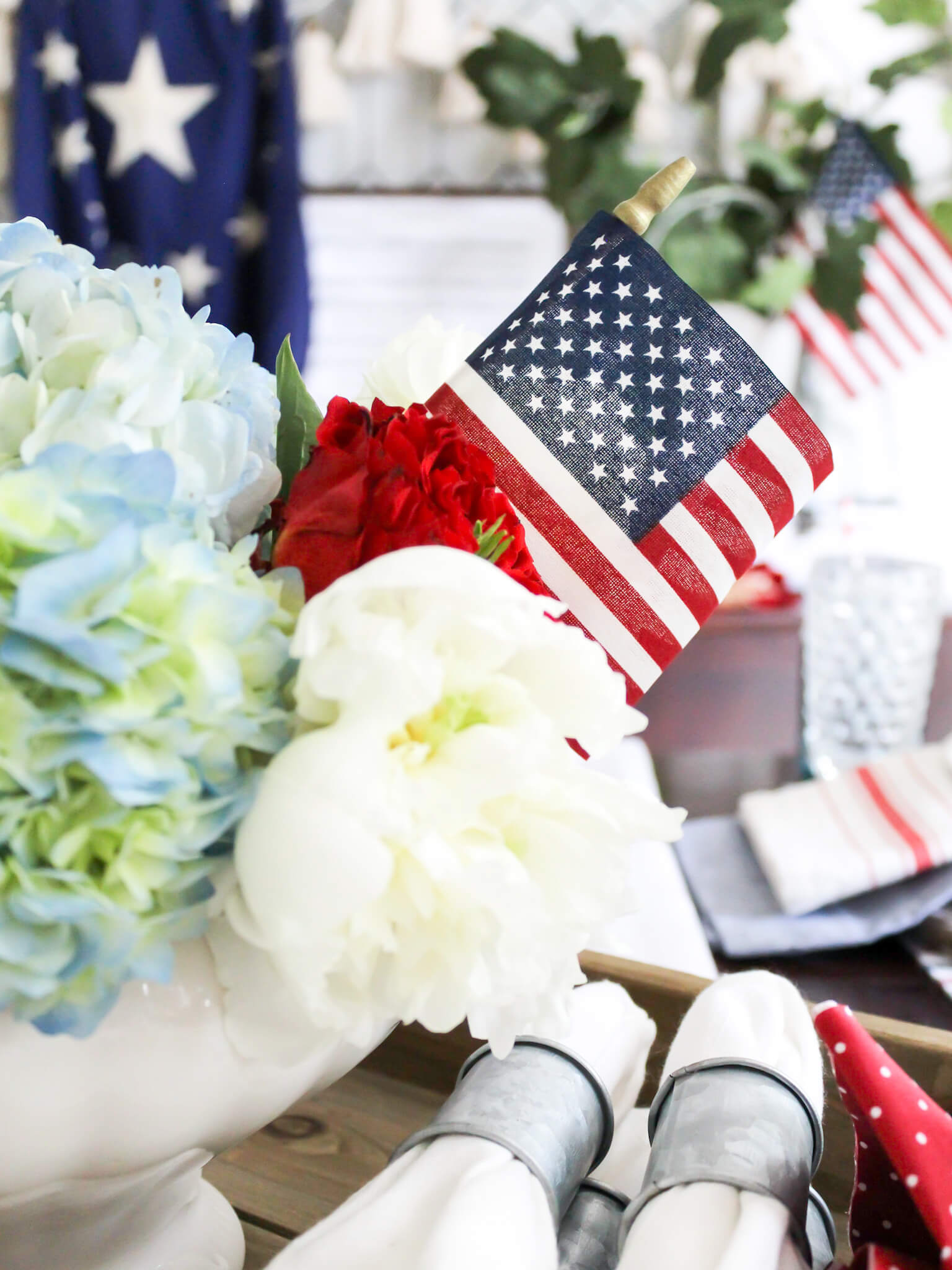 Close up of red, white and blue flowers with a small American flag on a patriotic tablescape for Independence Day