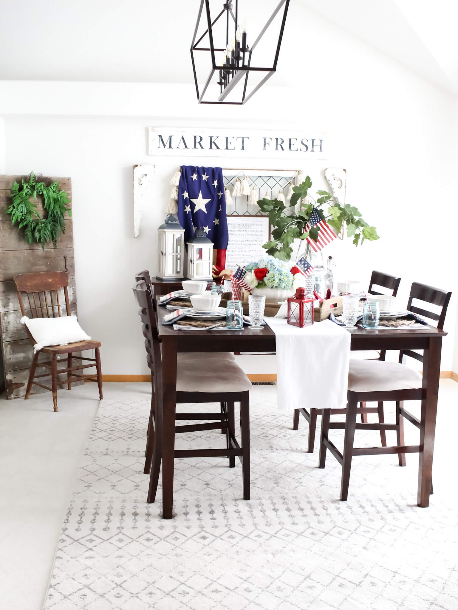 Farmhouse style formal dining room decorated with patriotic decor for the Fourth of July, including American flags and an elegant tablescape