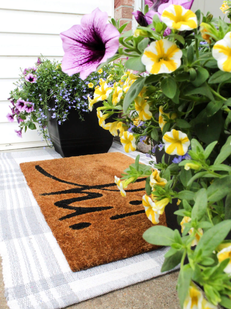 Purple and yellow planters on front porch with layered doormats - Midwest Life and Style Blog