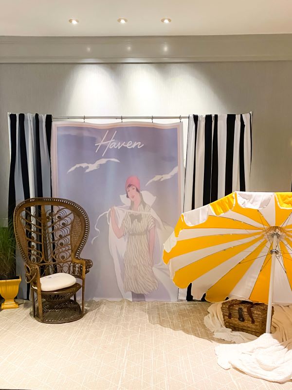 20's themed Haven photo booth with striped beach umbrella and rattan chair. 