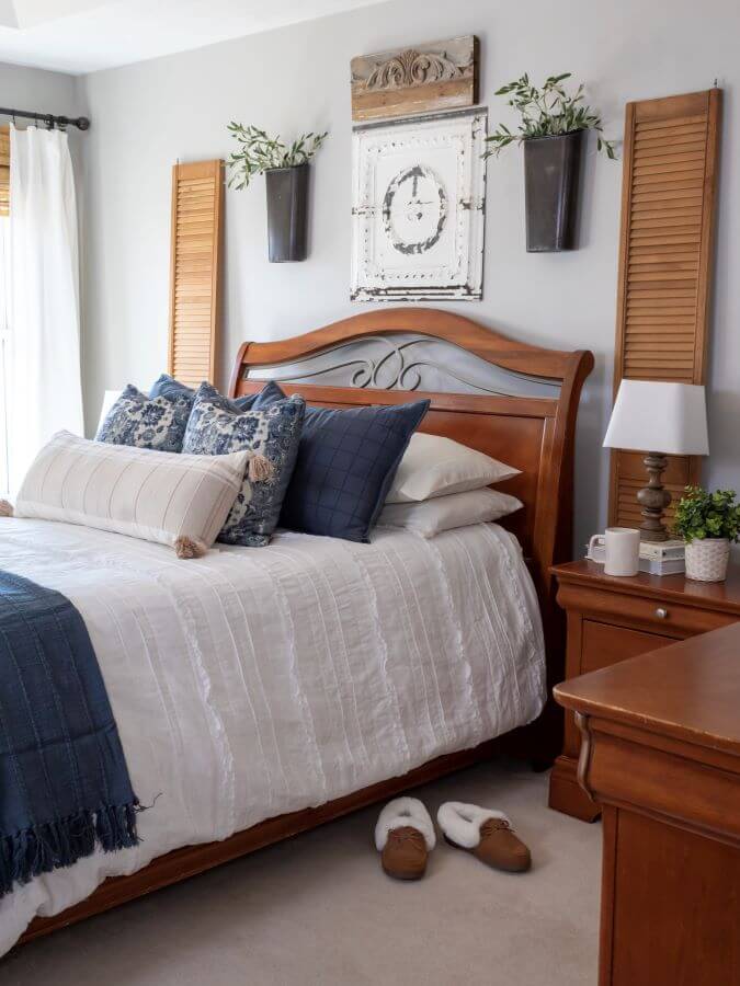 Bedroom decorated for spring with blue and white bedding and greenery in wall planters hanging above the bed