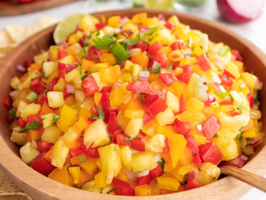 Close up view of bowl of Pineapple Jalapeño Salsa with a spoon 