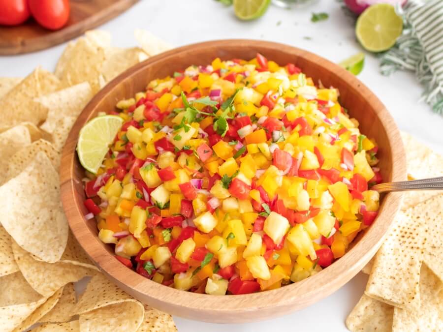 Bowl of Pineapple Jalapeño Salsa with a spoon and Tortilla Chips