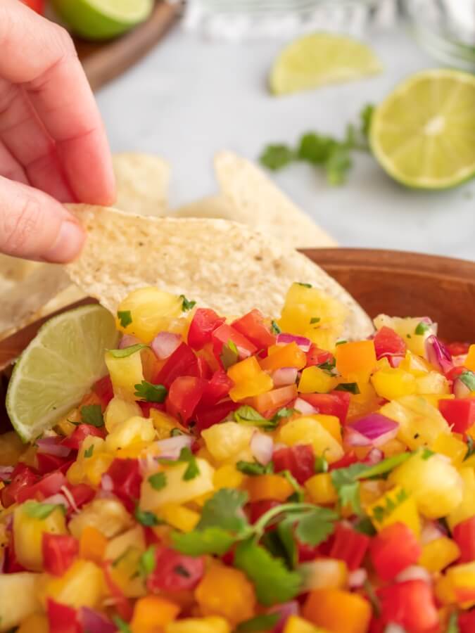 Hand dipping a tortilla chip into the Pineapple Jalapeño Salsa