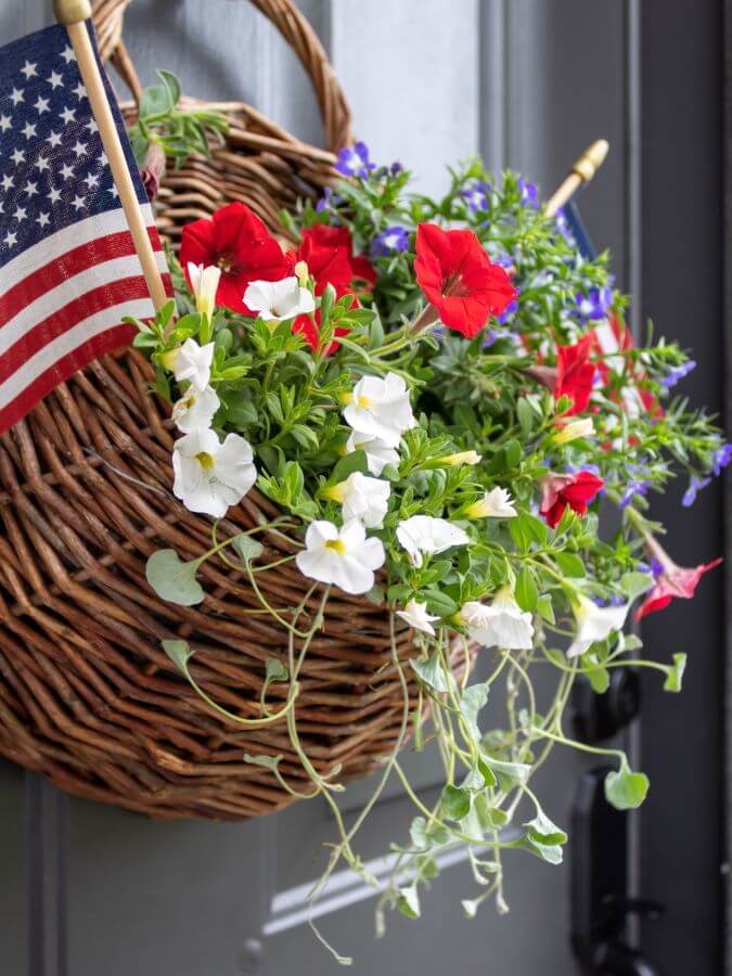 Close-Up Side View of a Hanging Door Basket with Red, White and Blue Summer Flower and American Flags for the 4th of July