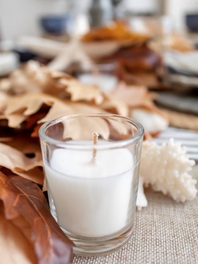 Close up view of fall leaf and seashell garland centerpiece for a coastal table setting with tea lights 