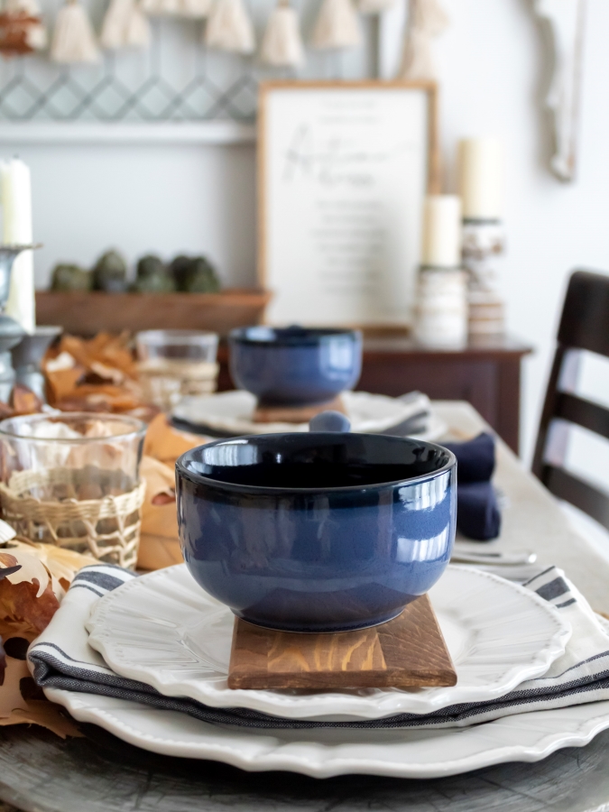 Blue soup bowls on a small bread board with with with white dishes for a coastal fall place setting