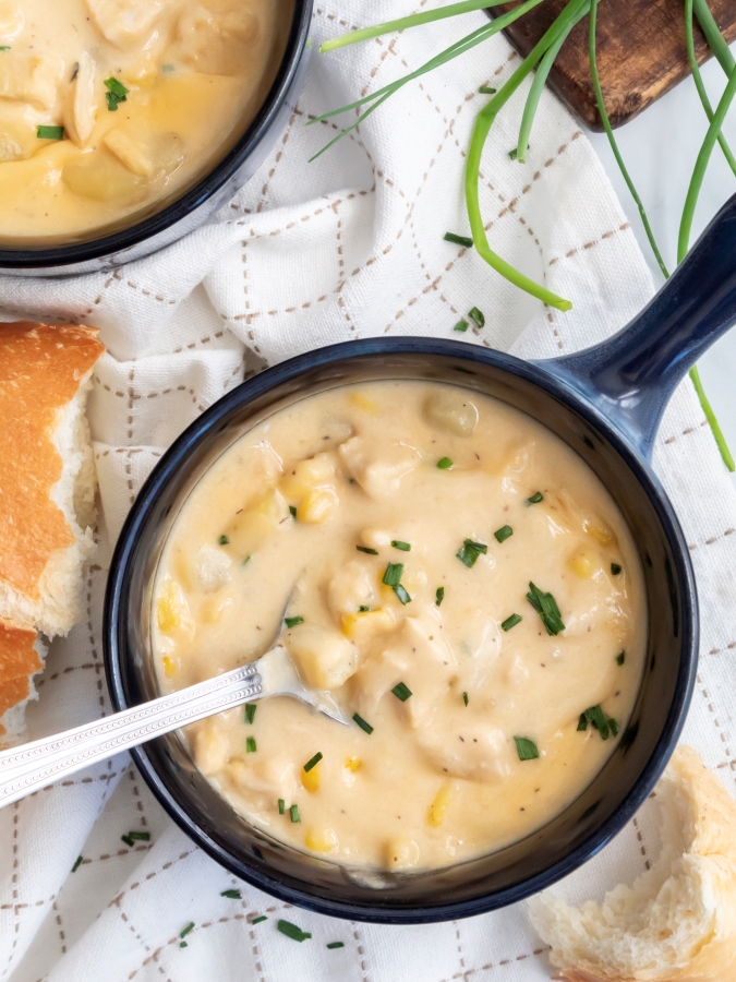 Overhead view of a bowl of Creamy Chicken and Corn Chowder served with french bread