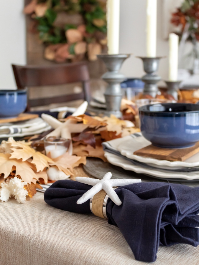 Close up view of DIY coastal napkin rings with starfish glued on silver and rattan napkin ring