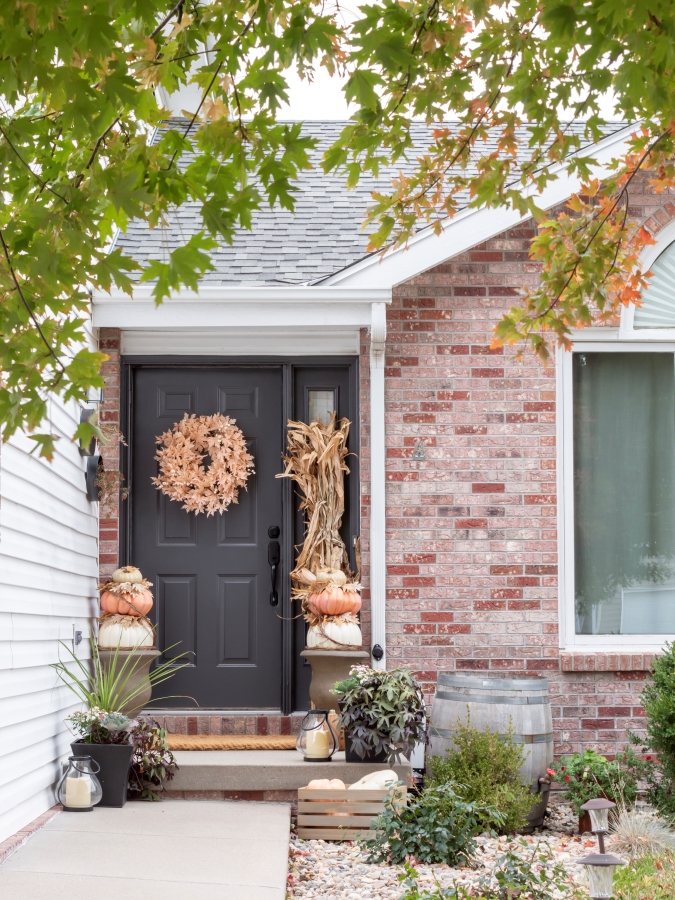 Fall porch with cornstalks, DIY stacked pumpkin topariies, an oak leaf wreath on the front door and fall planters. 