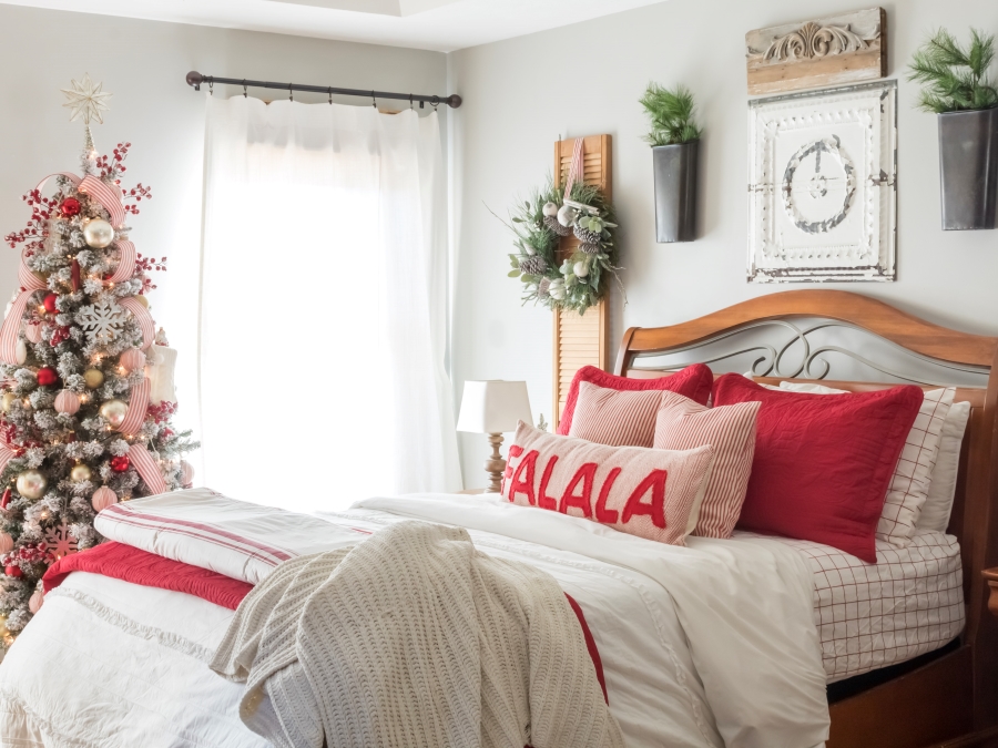 Red and white Christmas dedroom with flocked tree decorated with red and white ornaments and ticking stripe ribbon