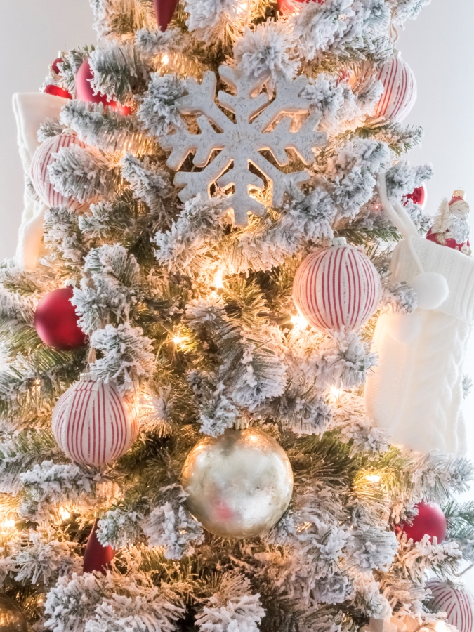 Decorating a flocked Christmas tree with white and red ornaments