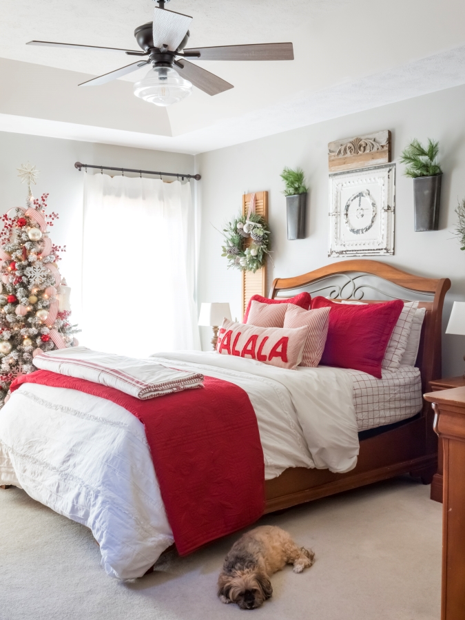 Bedroom decorated for Christmas with red and white holiday decor and a flocked Christmas tree