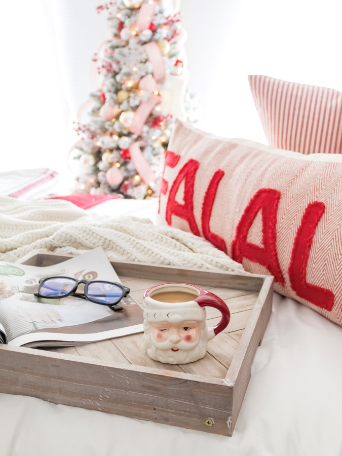 Bedroom decorated for Christmas with red and white decorations, Christmas bedding, and breakfast tray on the bed with a santa mug filled with coffee