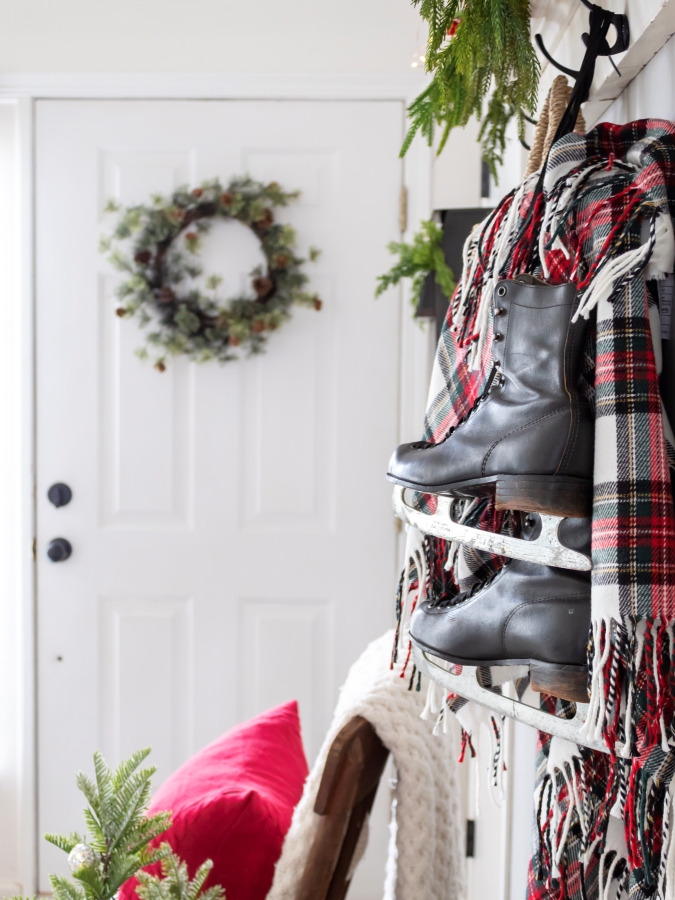 Vintage Ice Skates with a Red and White Plaid Blanket and Christmas Greenery Hangning From a Wood Shelf - Midwest Life and Style Blog