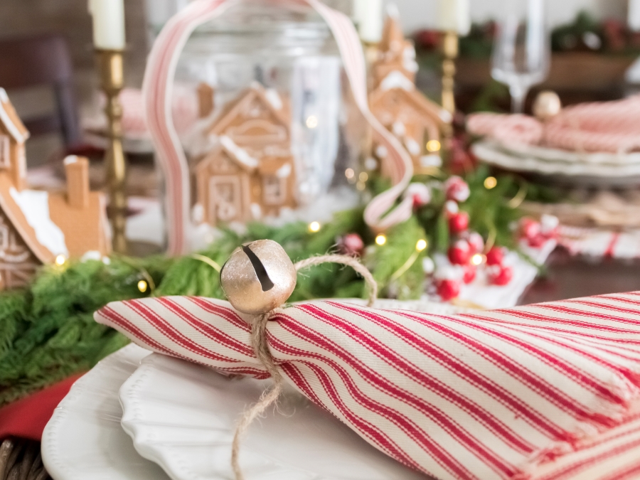 Gold Bell Tied Around Red and White Ticking Stripe Napkin On Chrismas Gingerbread Tablescape 