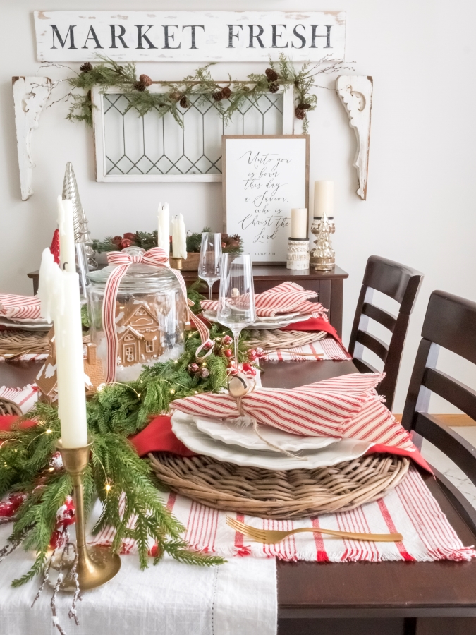 Red and white gingerbread Christmas tablescape with ticking stripe napkins, garland, vintage brass candlesticks and a DIY gingerbread snowglobe centerpiece