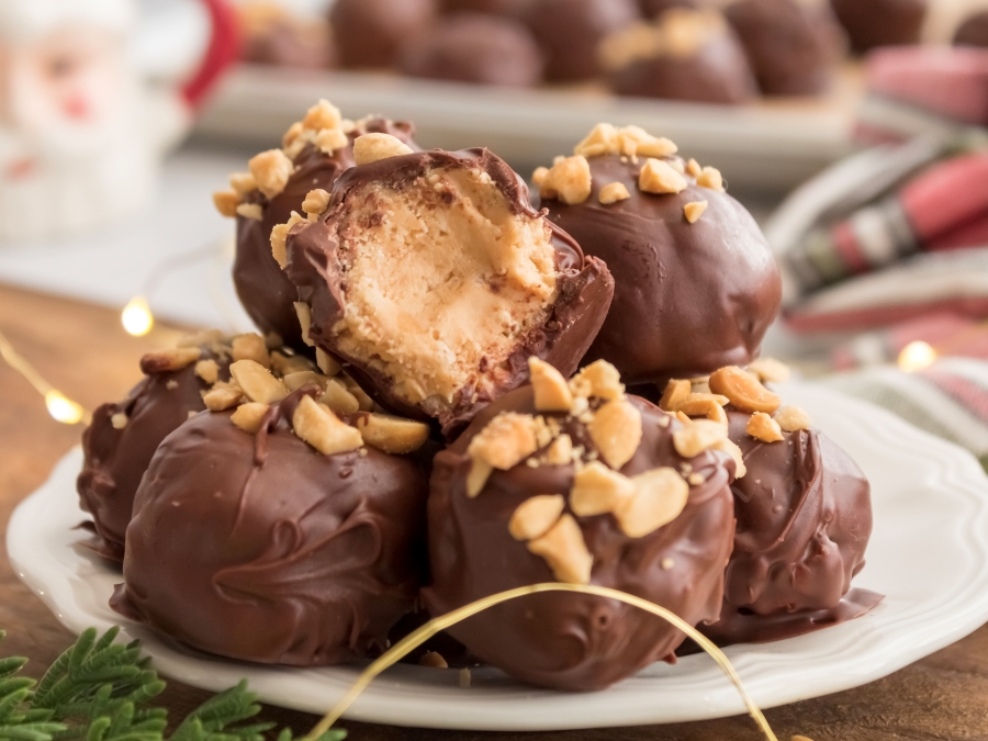 A plate of chocolate covered peantu butter balls topped with chopped peanuts