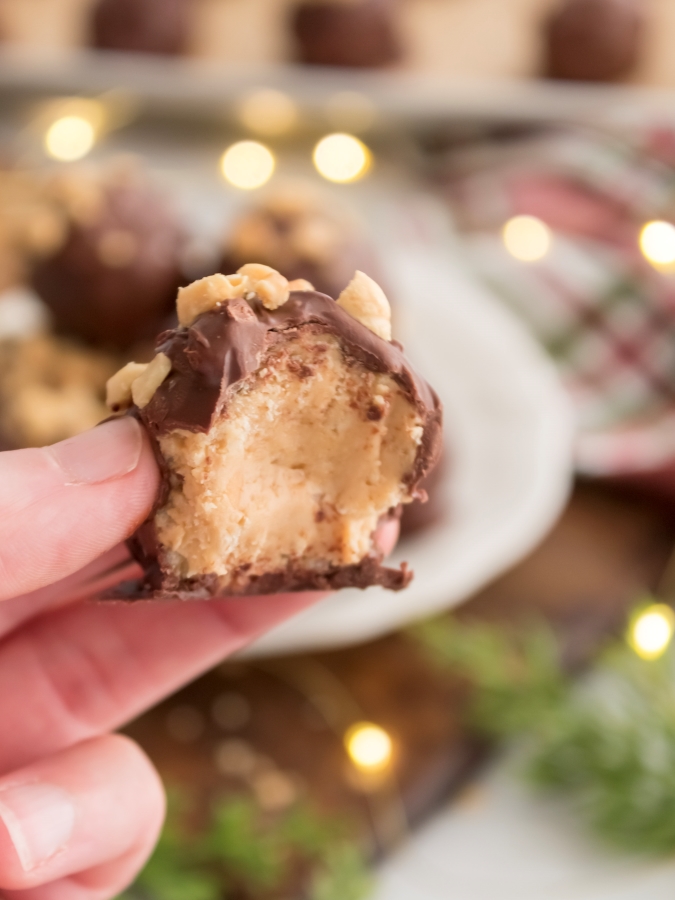 Holding a chocolate covered peanut butter ball with a bite taken out of it