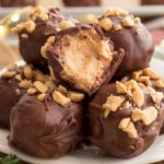 Chocolate Covered Peanut Butter Balls on a plate with a bite taken out of one of the PB balls