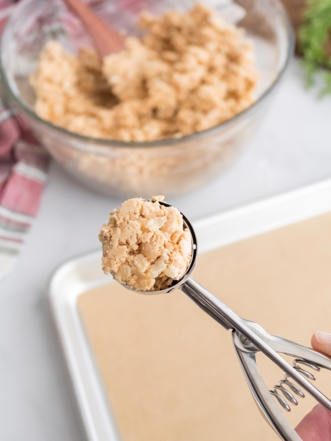 Using a cookie scoop to form the peanut butter filling for chocolate covered peanut butter balls