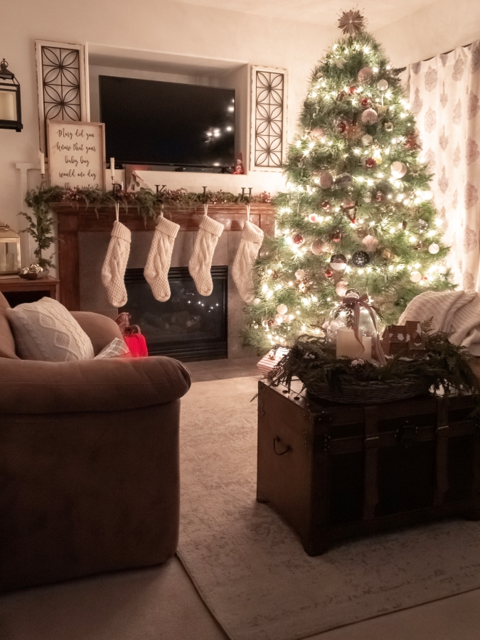 View of Christmas living room at night with the tree lit up and stockings hanging from the fireplace mantel