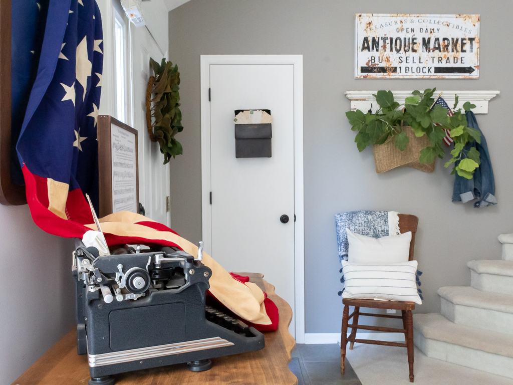 Front entry view with patriotic vignette display of flag and typewrite styled on an old dresser - Red White And Blue Summer Home Tour - Midwest Life and Style Blog