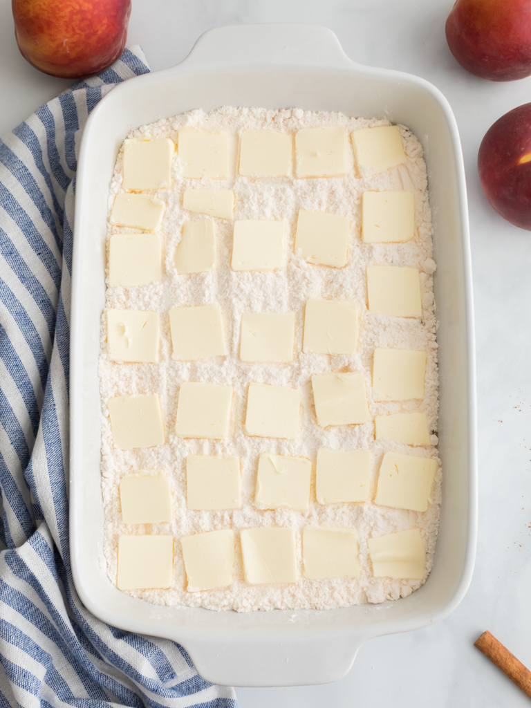 Adding the Slices of Butter on Top for Peach Dump Cake - Midwest Life and Style Blog