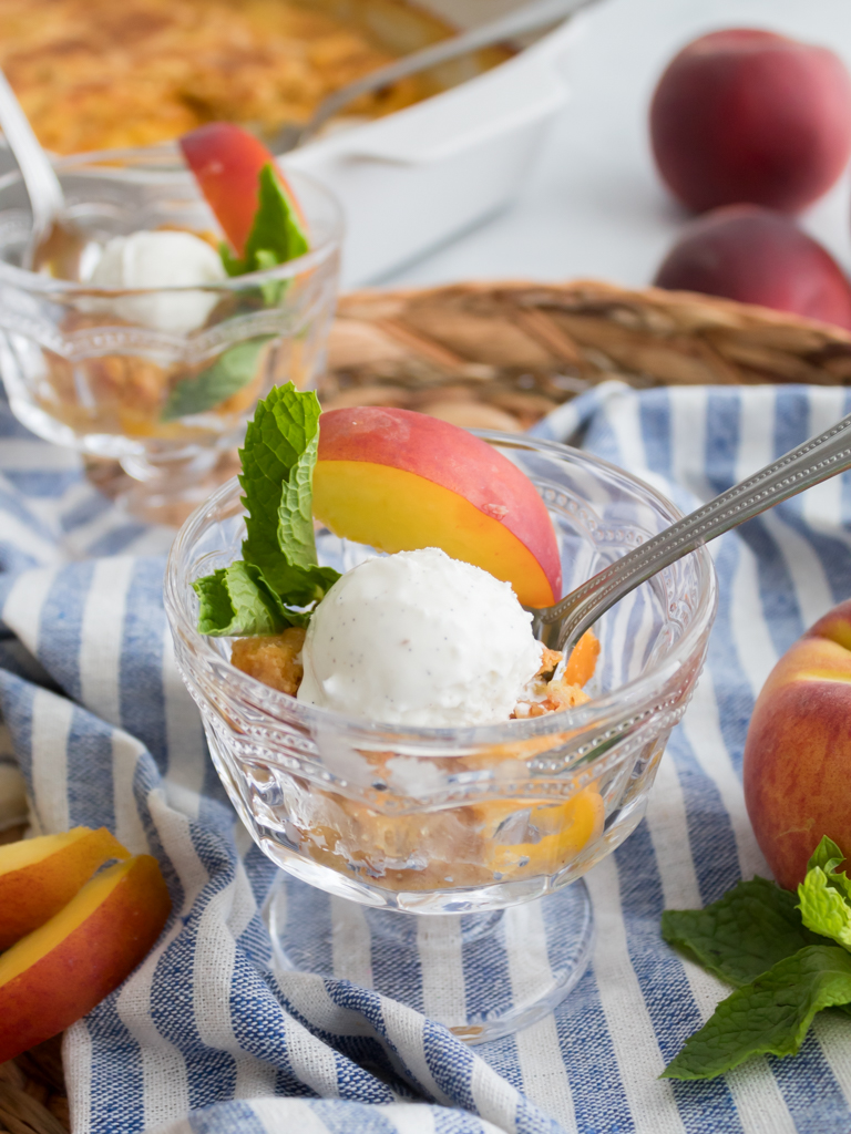 Peach dump cake served in a dessert cup topped with a scoop of vanilla ice cream 