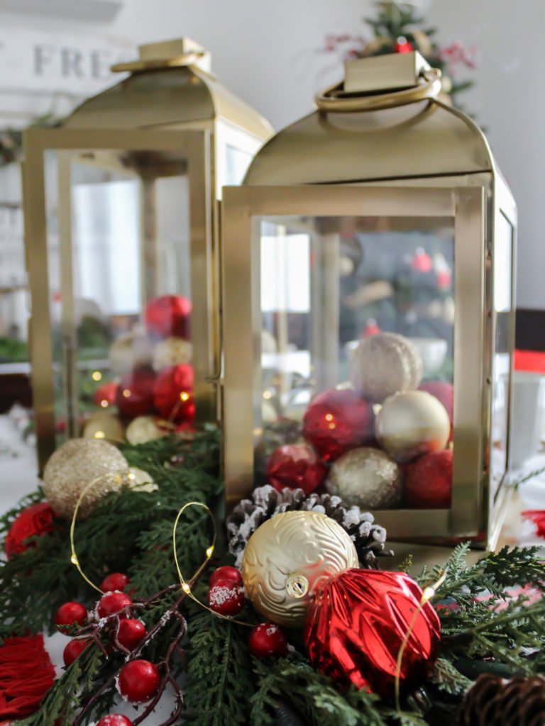 Simple and Festive Christmas Centerpiece Ideas - Gold Lanterns with Red and Gold Christmas Ornaments, Greenery, and Twinkle Lights